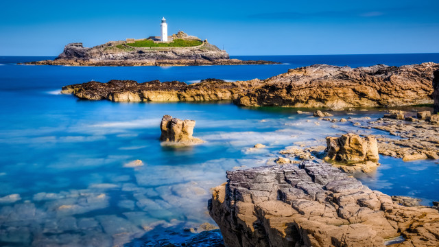 Lighthouse rocky shore blue water free wallpaper for desktop - medium preview image