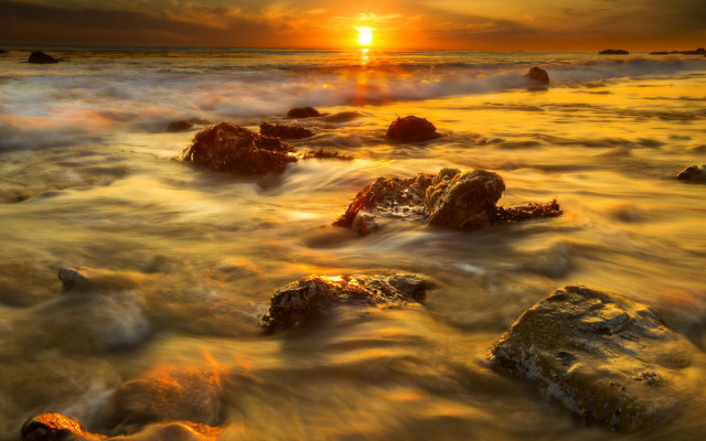 Sunset ocean rocks distant sun free wallpaper for desktop - medium preview image