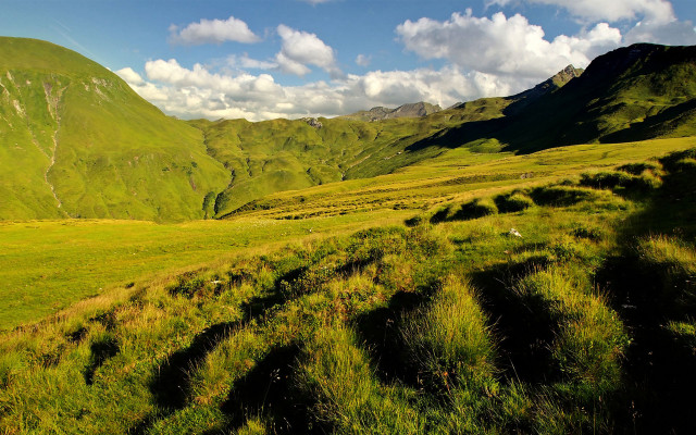 Grassy valley mountains clouds nature free wallpaper for desktop - medium preview image