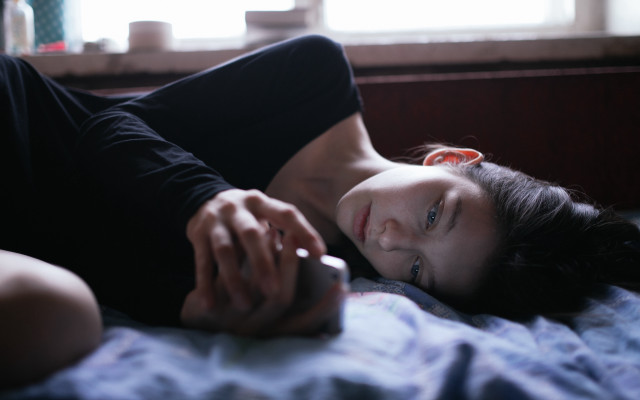 Woman lying bed holding phone free wallpaper for desktop - medium preview image