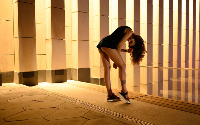 Woman leaning wall skirt sneakers free wallpaper for desktop - medium preview image