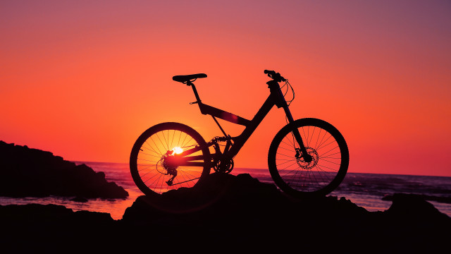 Bike rock sunset ocean person free wallpaper for desktop - medium preview image