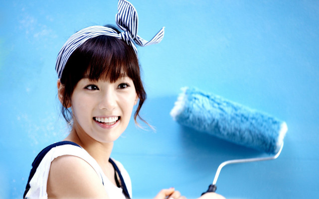 Cheerful woman painting blue wall free wallpaper for desktop - medium preview image