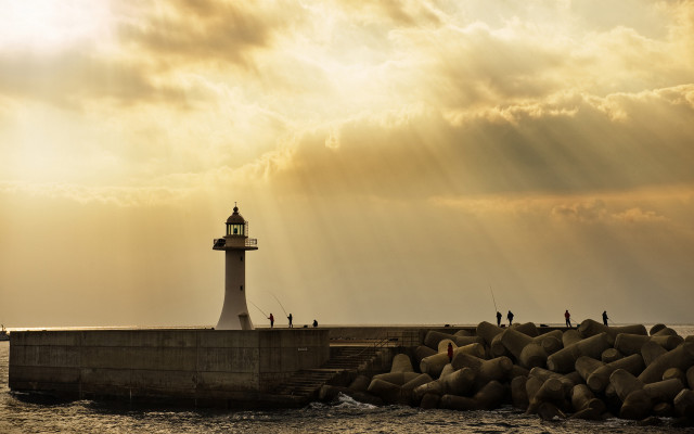 Lighthouse rocky pier sunset sunbeams free wallpaper for desktop - medium preview image