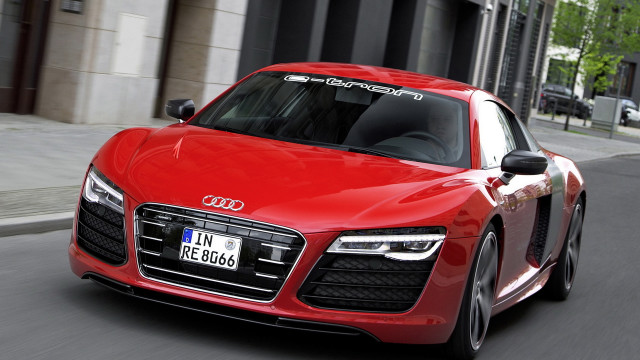 Red car driving tall building free wallpaper for desktop - medium preview image