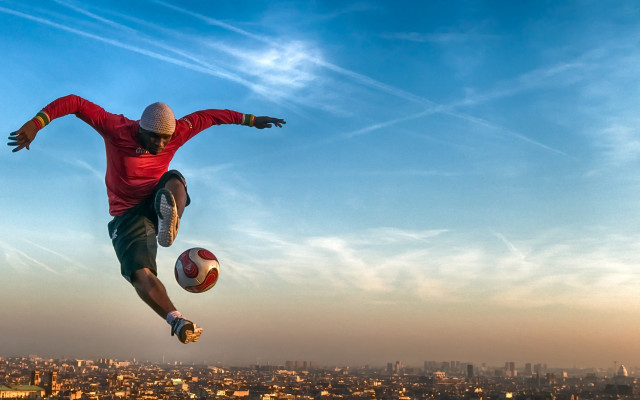 Man jumping soccerball city background free wallpaper for desktop - medium preview image