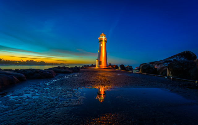 Lighthouse rocky shore sunset reflection free wallpaper for desktop - medium preview image