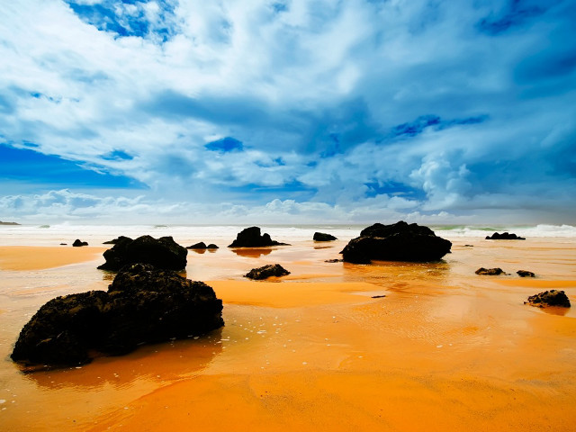 Sandy beach rocks water cloudy free wallpaper for desktop - medium preview image