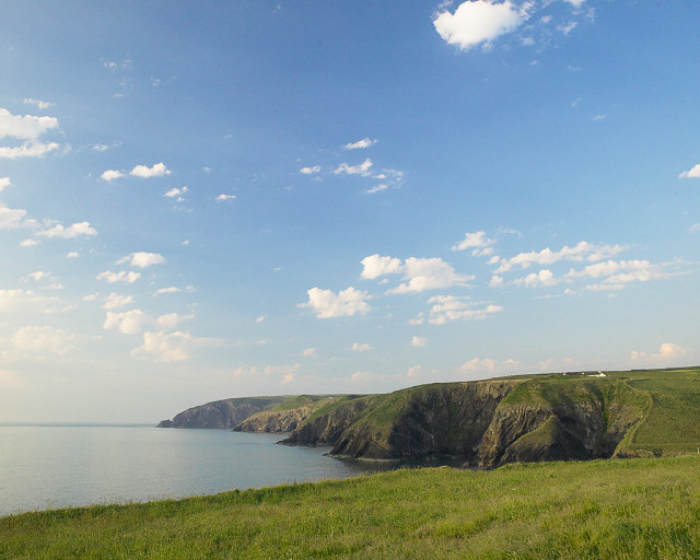 Grassy field water cliff sky free wallpaper for desktop - medium preview image