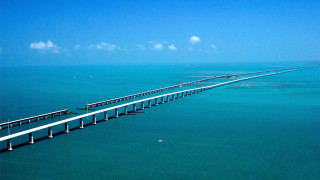 Long bridge spanning ocean blue - a blue sky above free wallpaper