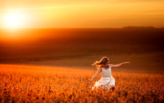 Woman field arms outstretched sunset - behind her free wallpaper