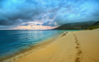 Beach footprints water mountain clouds - the water and a mountain in the distance free wallpaper