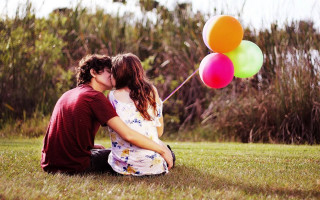 Couple grass balloons kissing smiling - a couple sitting free wallpaper