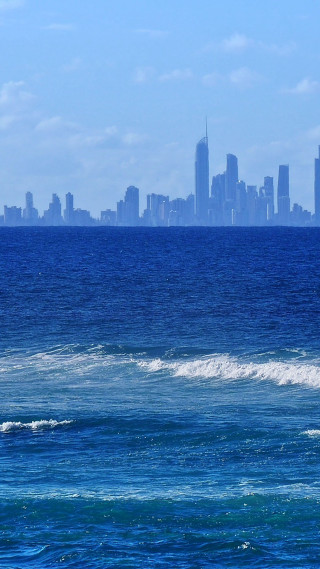 Man surfboard wave ocean city - panoramic free wallpaper for mobile