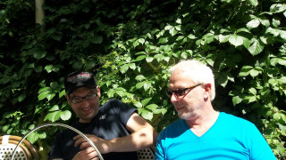 Two men bench bush green - one holding free wallpaper