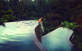 Man sitting ledged pool jungle - a waterfall in the background and trees free wallpaper