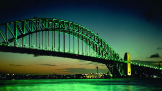 Large green bridge night water - side and a city in the background free wallpaper