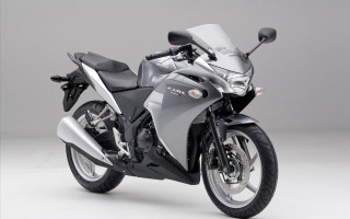 Silver motorcycle parked white surface - a gray background behind free wallpaper