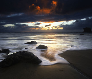 Sunset beach rocks water dark - a sunset over a beach free wallpaper for desktop