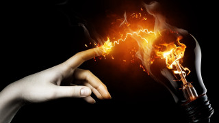 Hand holding lightbulb flame pointing - a light bulb free wallpaper