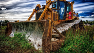 Bulldozer parked field cloudy sky 2 - a cloudy sky in the background free wallpaper
