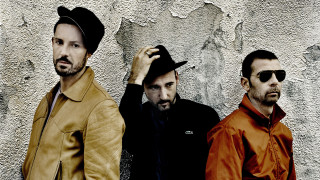 Three men wall hat standing - a wall behind them free wallpaper