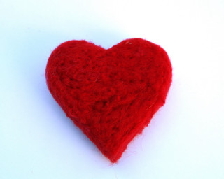Red heart white surface background - a cross stitch free wallpaper