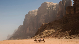 Three people horses desert mountains - a blue sky above them free wallpaper