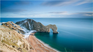 Beach rock formation water body - a rock formation in the middle of it free wallpaper