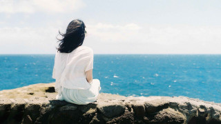 Woman sitting rock ocean cliff 2 - the wind free wallpaper