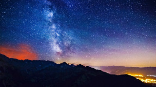 Night sky star filled mountains 2 - a city below free wallpaper for desktop