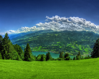 Green field lake mountains clouds - a lake in the middle of it free wallpaper