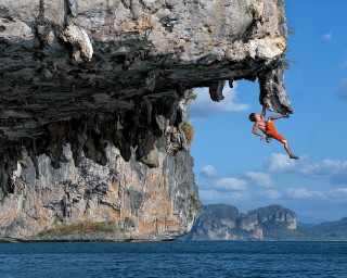 Man jumping cliff ocean background - amazing free wallpaper