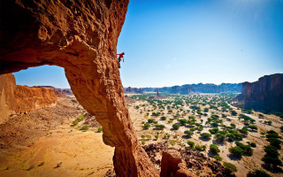 Man climbing cliff desert valley 2 - tree below free wallpaper
