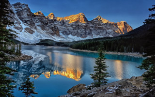 Mountain lake trees rocks foreground - the foreground and a mountain range in the background free wallpaper