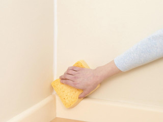 Person cleaning corner wall sponge - a hand holding free wallpaper