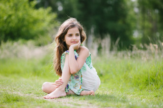 Little girl sitting grass arms - the ground in a field of grass free wallpaper