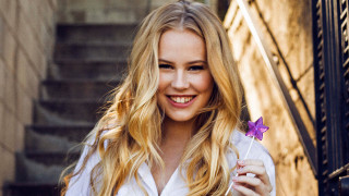 Woman holding purple flower smiling - amalia lindegren free wallpaper