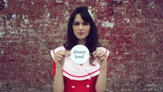 Woman holding sign dream land - it in front free wallpaper