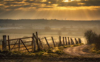 Dirt road fence field sunbeam - a fence and a field in the background free wallpaper