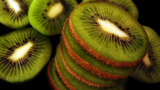 Kiwi slices stacked black surface - white dot free wallpaper