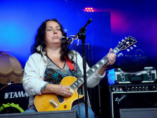 Woman playing guitar stage microphone - a blue light behind her free wallpaper