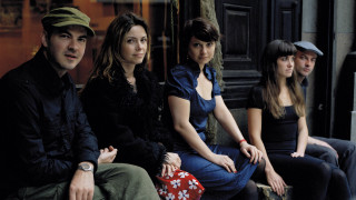 Group people bench building clock - a group of people sitting next free wallpaper