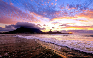 Sunset beach waves mountains clouds - a sunset over a beach free wallpaper for desktop