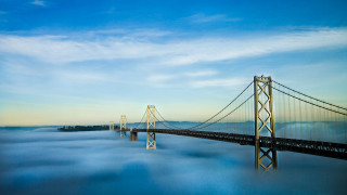 Bridge foggy day blue sky - a few cloud below free wallpaper for desktop