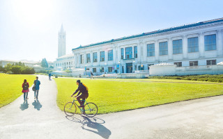 Man riding bike sidewalk green - a large white building free wallpaper