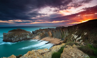 Sunset rocky beach water cliff - a sunset over a rocky beach free wallpaper