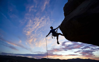 Man climbing cliff sunset sky - a rope free wallpaper