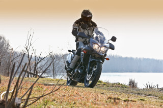 Man motorcycle grassy hill lake - a lake in the background free wallpaper for desktop