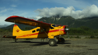 Small yellow airplane mountains clouds - front view free wallpaper